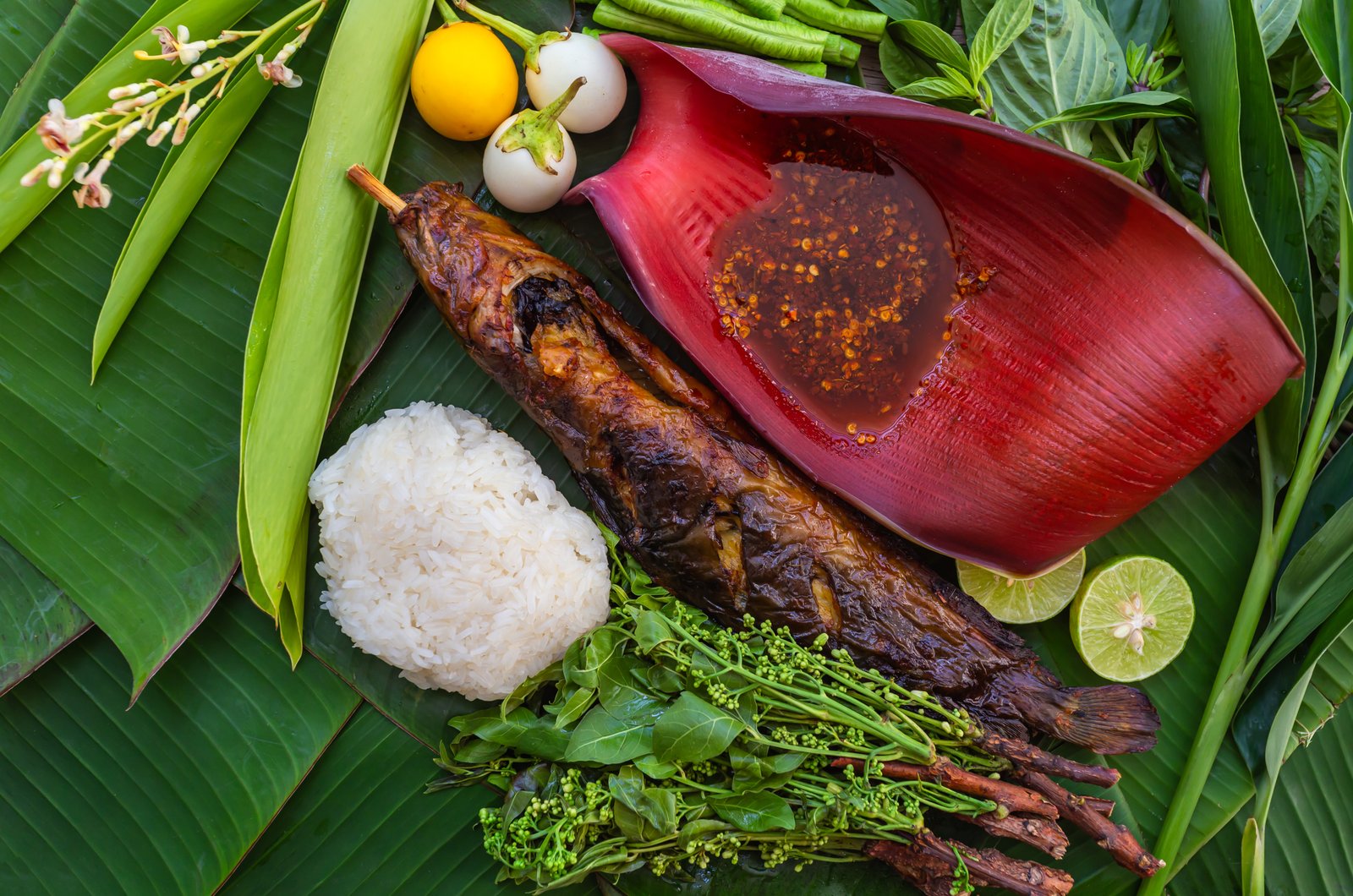Grilled catfish with sticky rice and vegetables placed on a banana leaf from the top view,Local food in rural Thailand